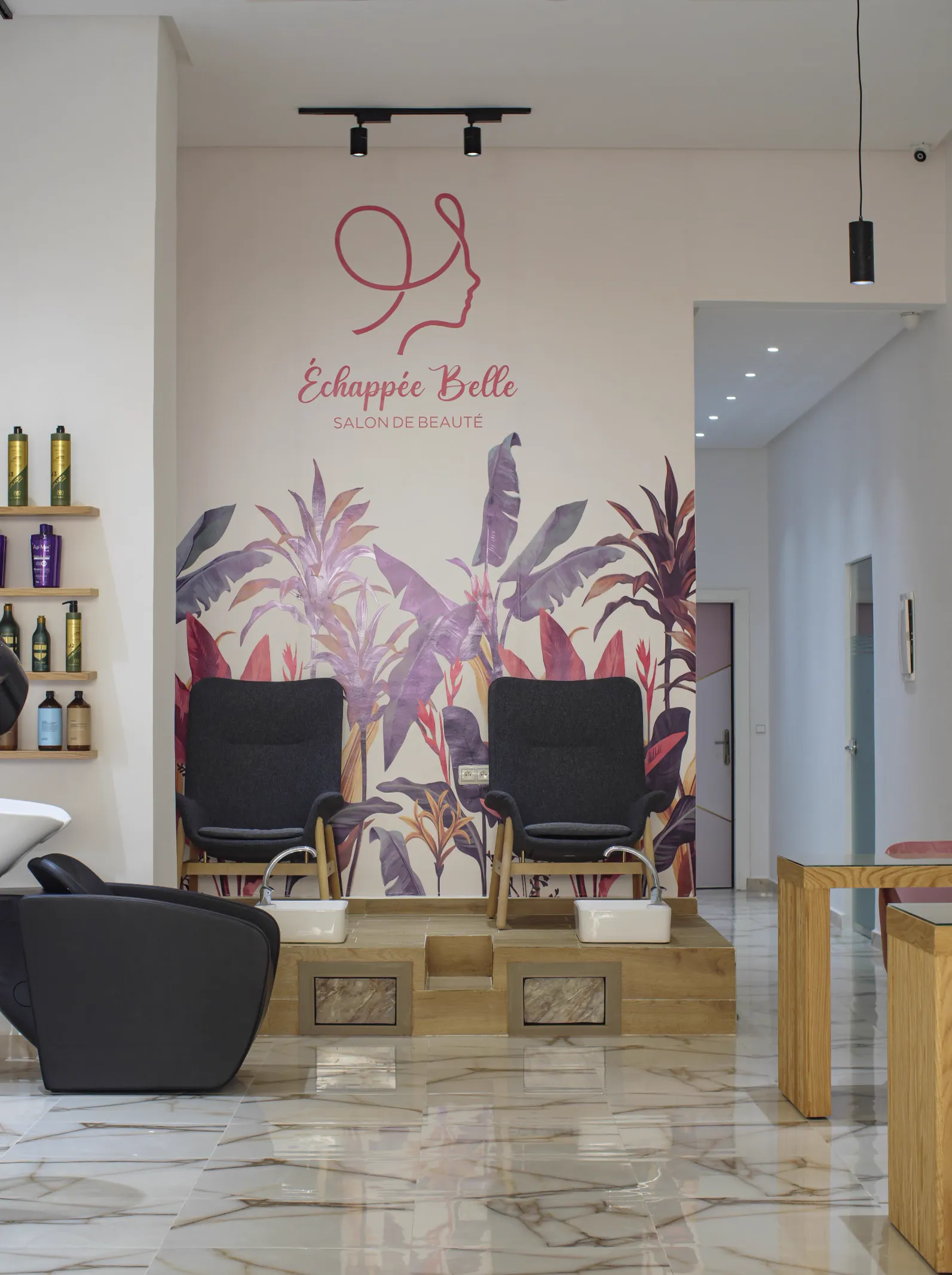 Le salon Échappée Belle : fauteuils de pédicure devant la fresque tropicale